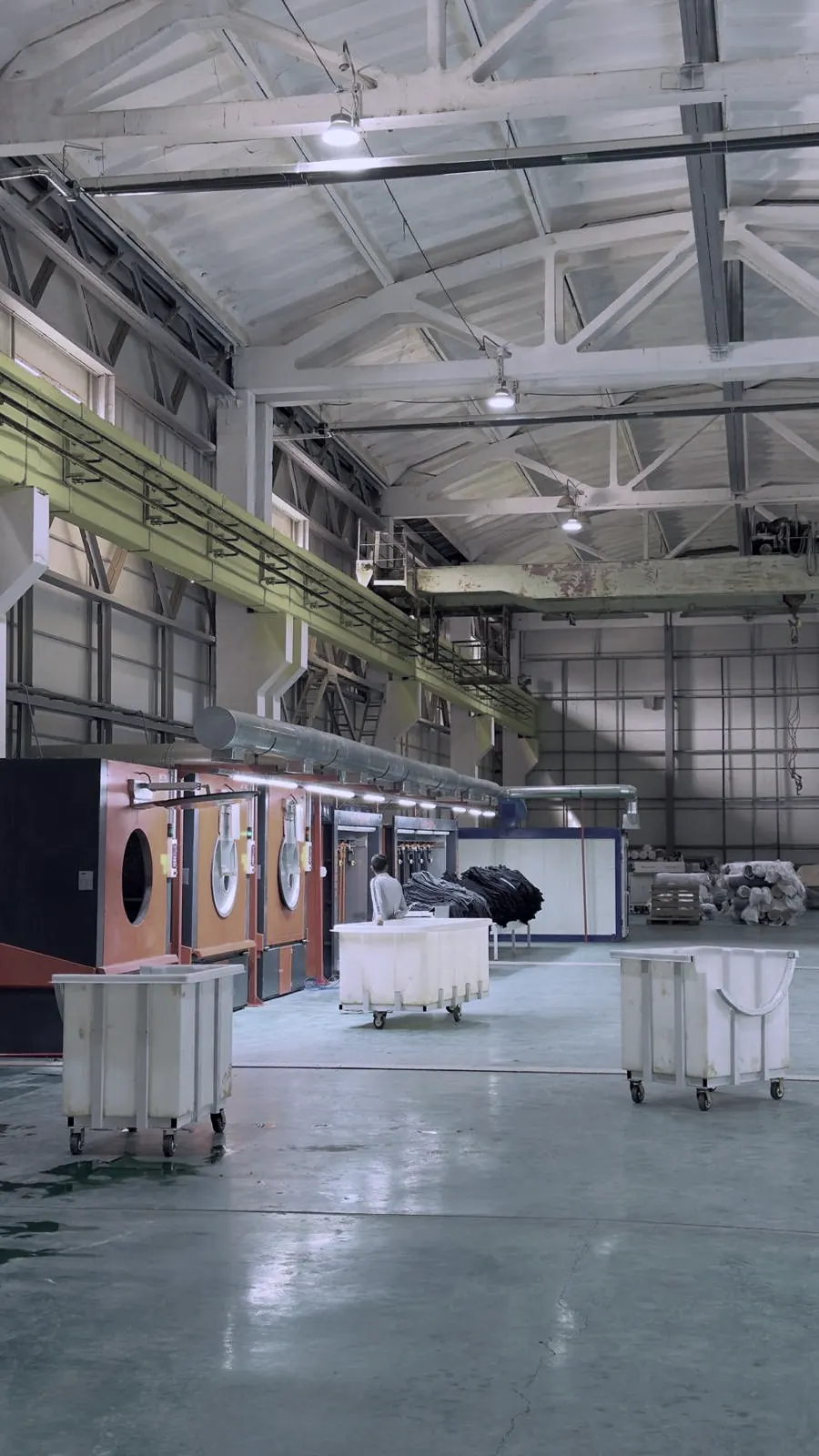 Rows of commercial washers and linen carts across a large laundry facility floor