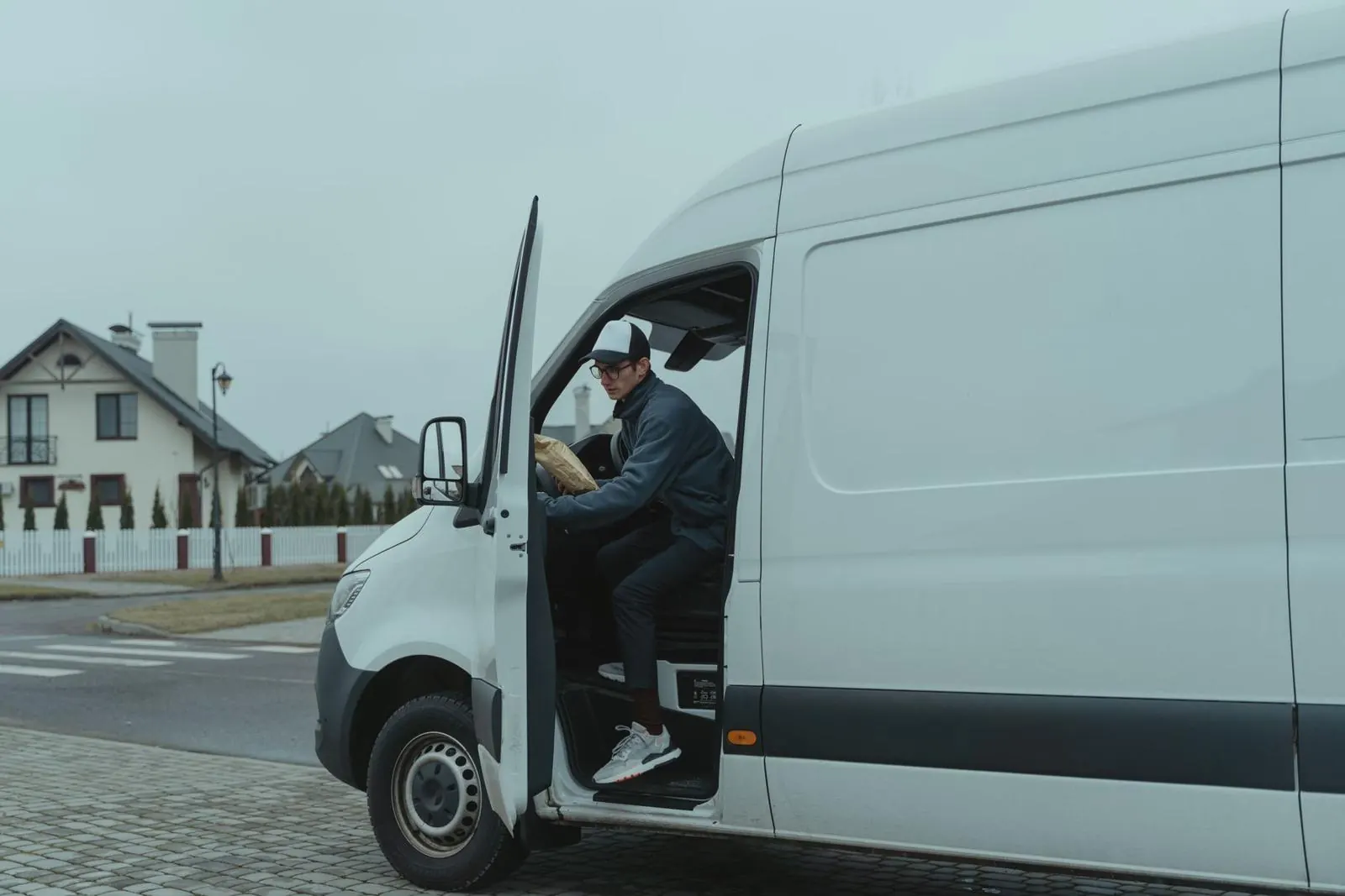 A driver stepping out of a white delivery van
