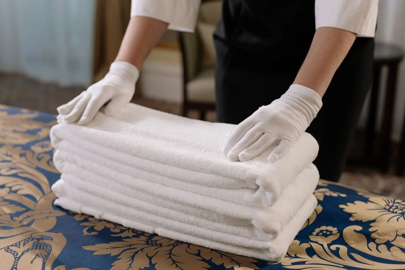 Gloved hands squaring a stack of folded white towels
