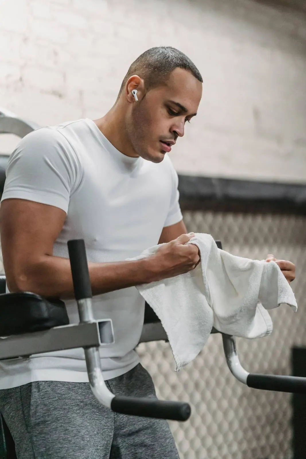 A man wiping his hands with a white towel at the gym