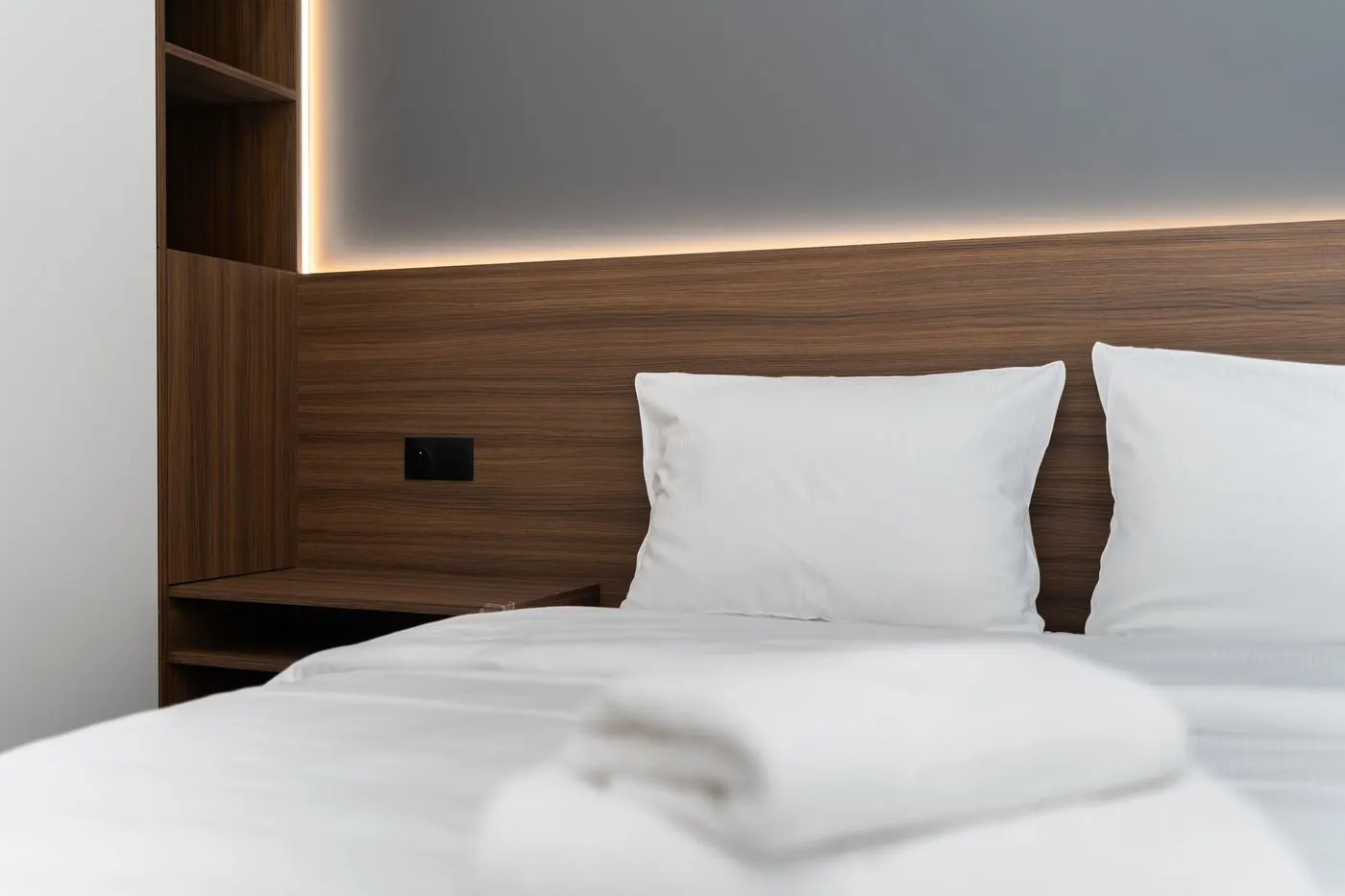 A hotel bed made with crisp white sheets and a folded towel