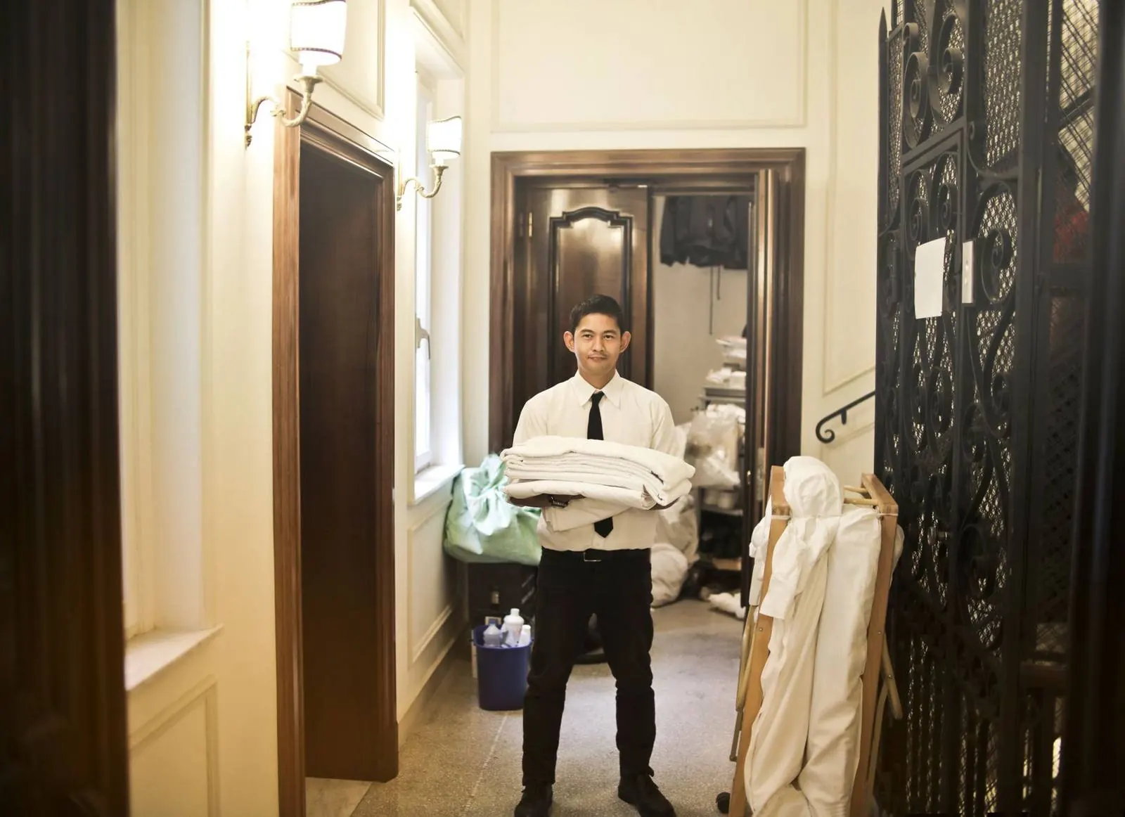 A hotel staff member carrying a stack of fresh white linens