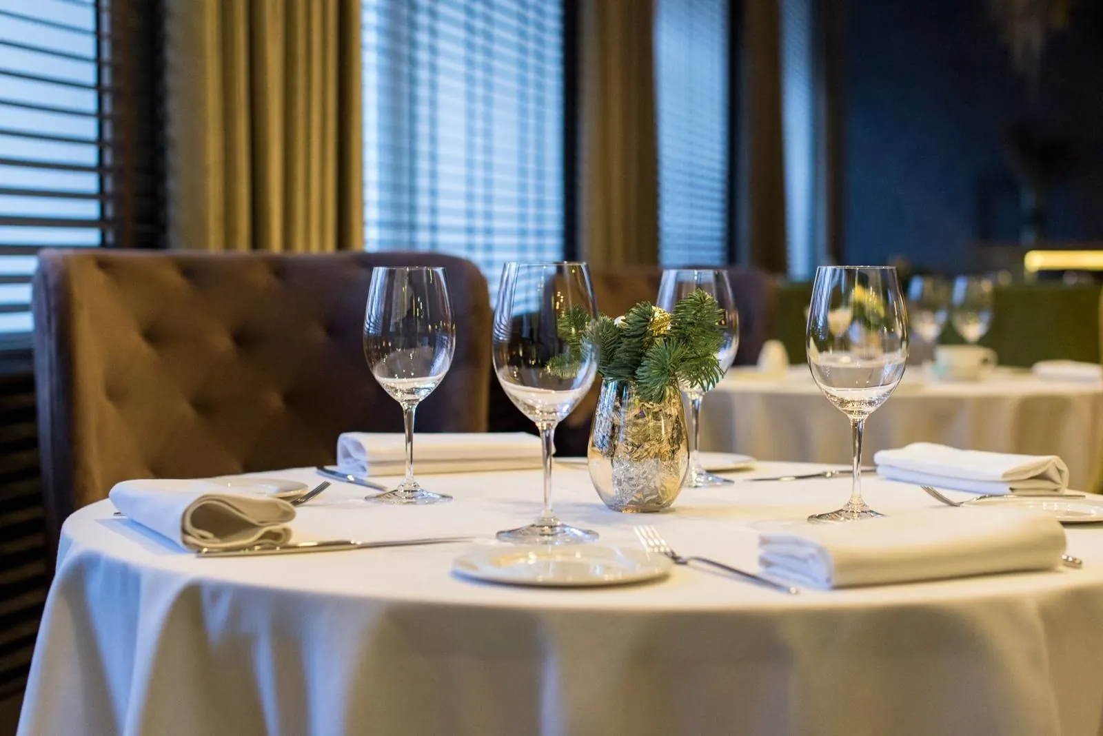 A round banquet table set with white linens, napkins and glassware