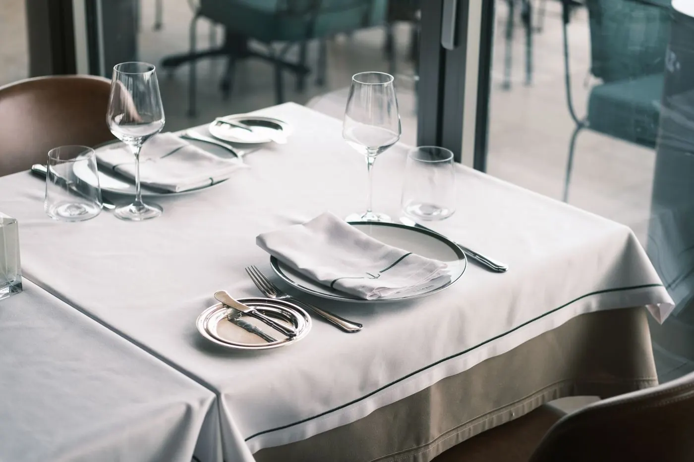 A restaurant table set with a white tablecloth and folded napkins
